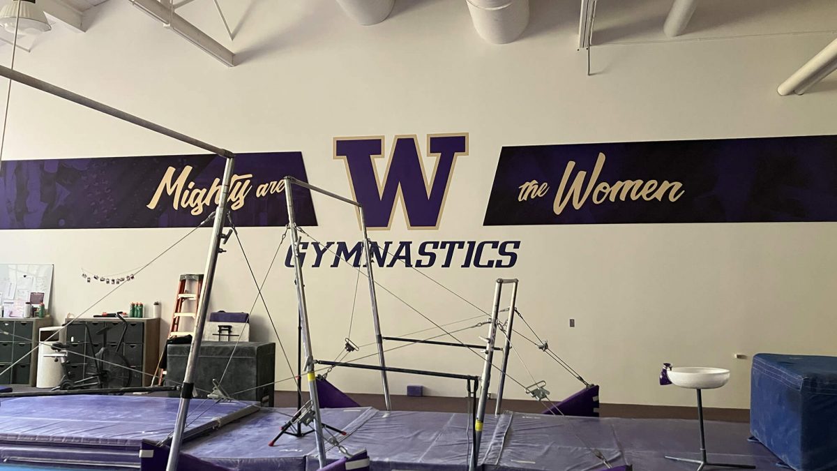 University of Washington Gymnastics wall mural, produced and installed by SuperGraphics. Showcases branded graphics and logos withe messaging, "Mighty the Women."