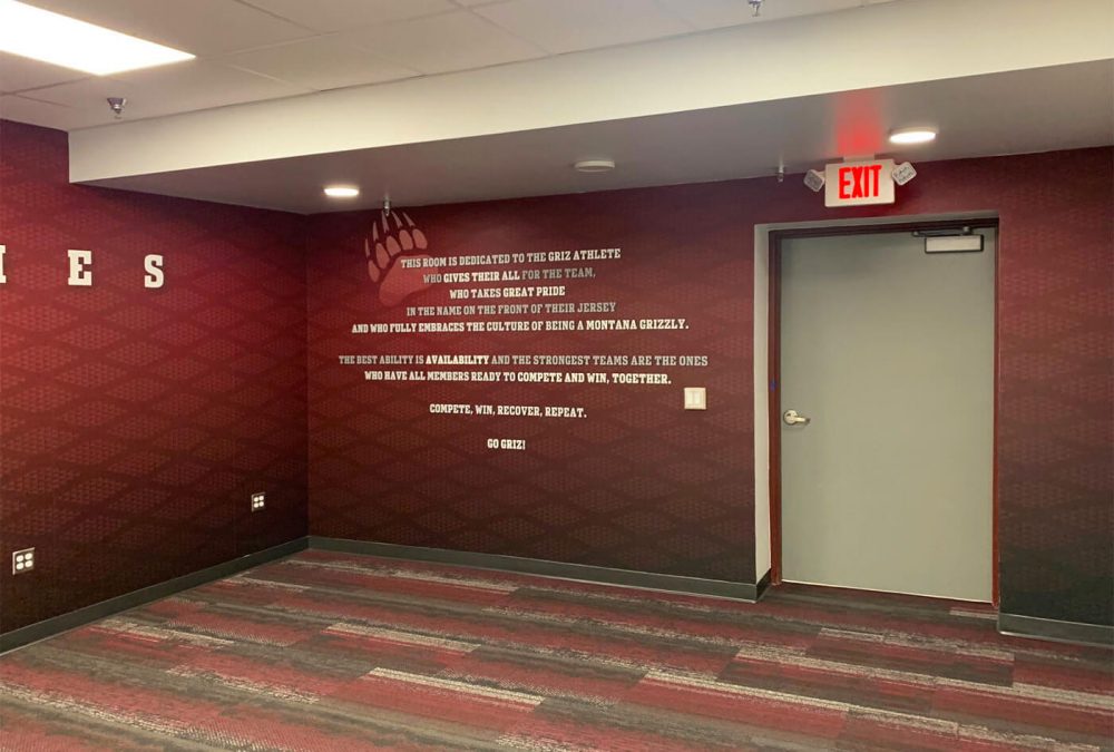 University of Montana Athletics Facility branding, produced and installed by SuperGraphics. Showcases athletics mission statement on branded red wall mural.