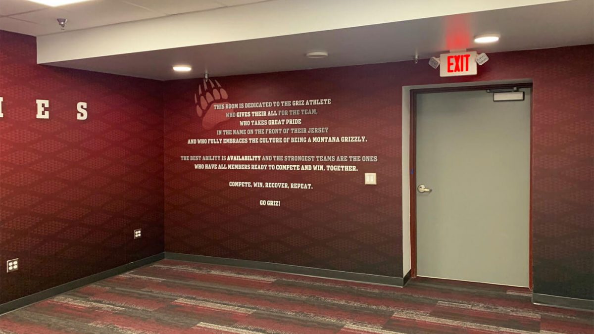 University of Montana Athletics Facility branding, produced and installed by SuperGraphics. Showcases athletics mission statement on branded red wall mural.