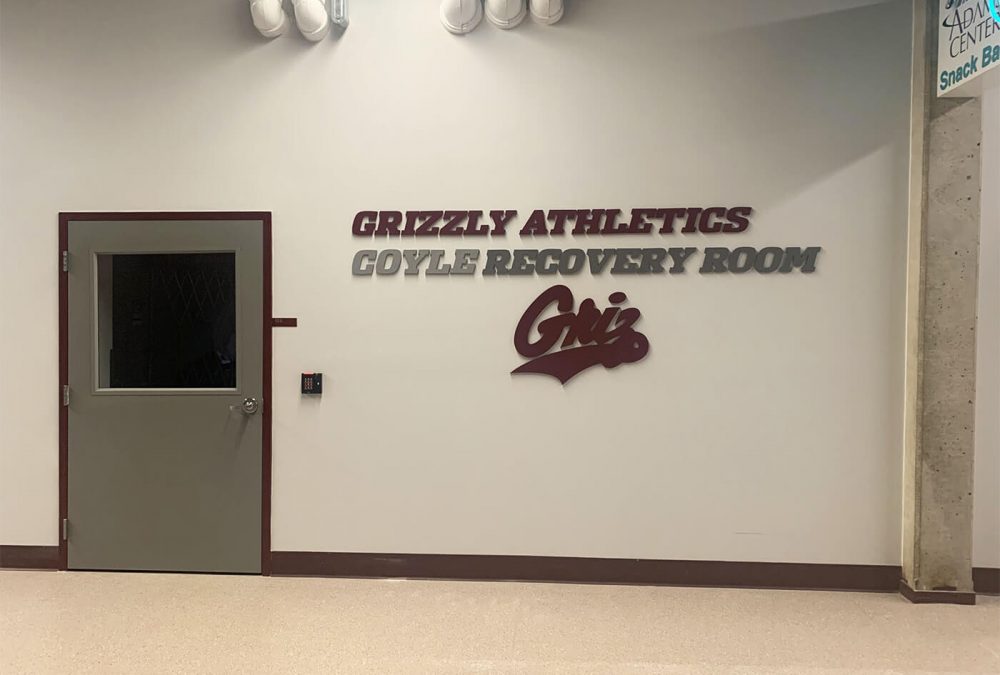 University of Montana Athletics recover room signage, produced and installed by SuperGraphics. Showcases branded dimensional lettering and logo for room.