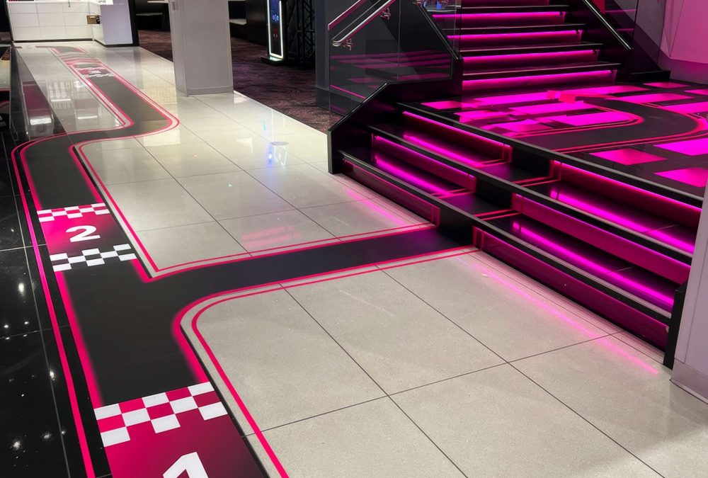 Dynamic floor graphics lead to a lit staircase in T-Mobile's flagship store, showcasing event graphics.