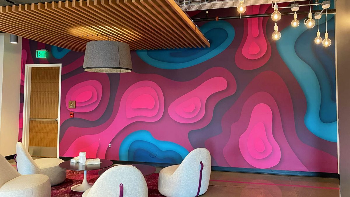 T-Mobile Corporate T-Mobile branded wall mural for corporate office, completed by SuperGraphics. Showcases magenta and blue topographic design in front of lounge area.