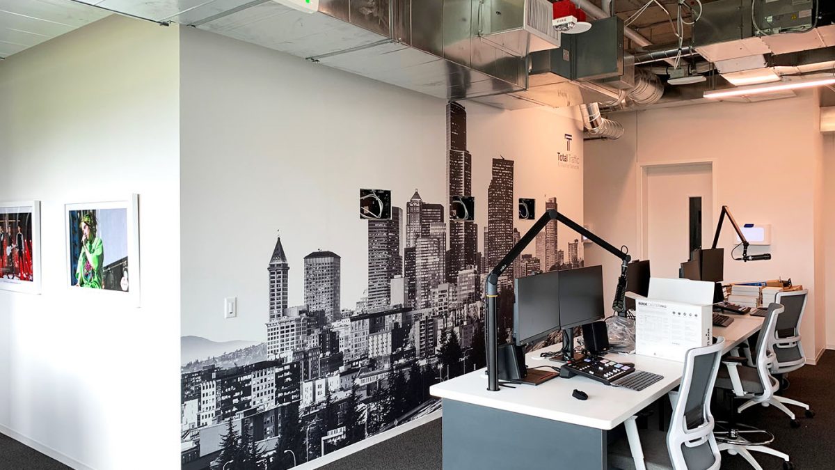 Photo of wall graphics at iHeart Media Seattle office, produced and installed by SuperGraphics. Showcases wall mural of Seattle skyline in black and white, in front of desks in a corporate office.