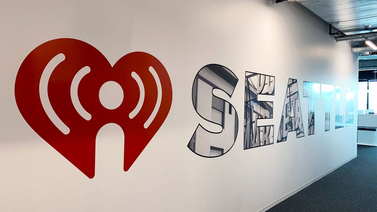 Photo of wall decals for iHeart Media Seattle office, produced and installed by SuperGraphics. Showcases reflective wall decals of iHeart Media logo and the letters "Seattle."