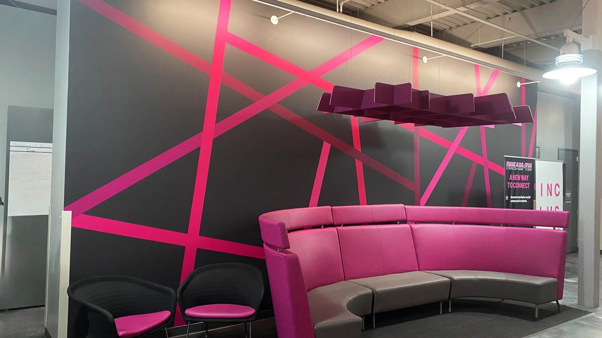 T-Mobile branded wall mural for corporate office, completed by SuperGraphics. Showcases magenta linear pattern in front of lounge area.